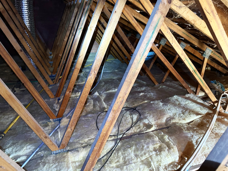 After: roof space with new insulation batts laid between timber trusses