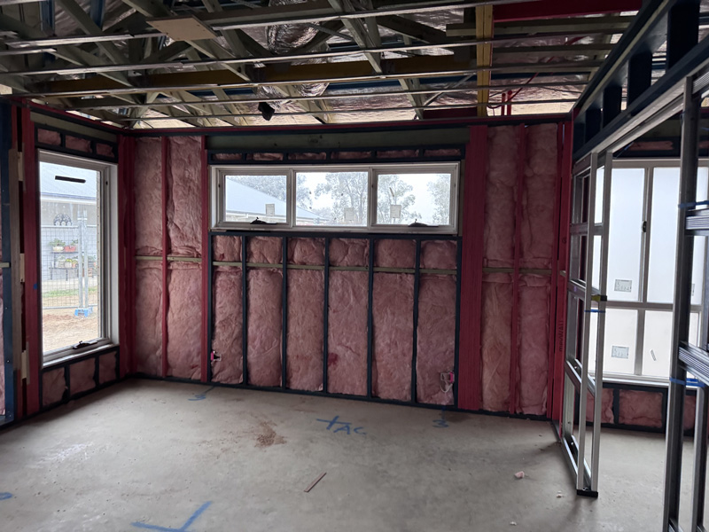 Pink wall batts around windows and a doorway in a new home's frame