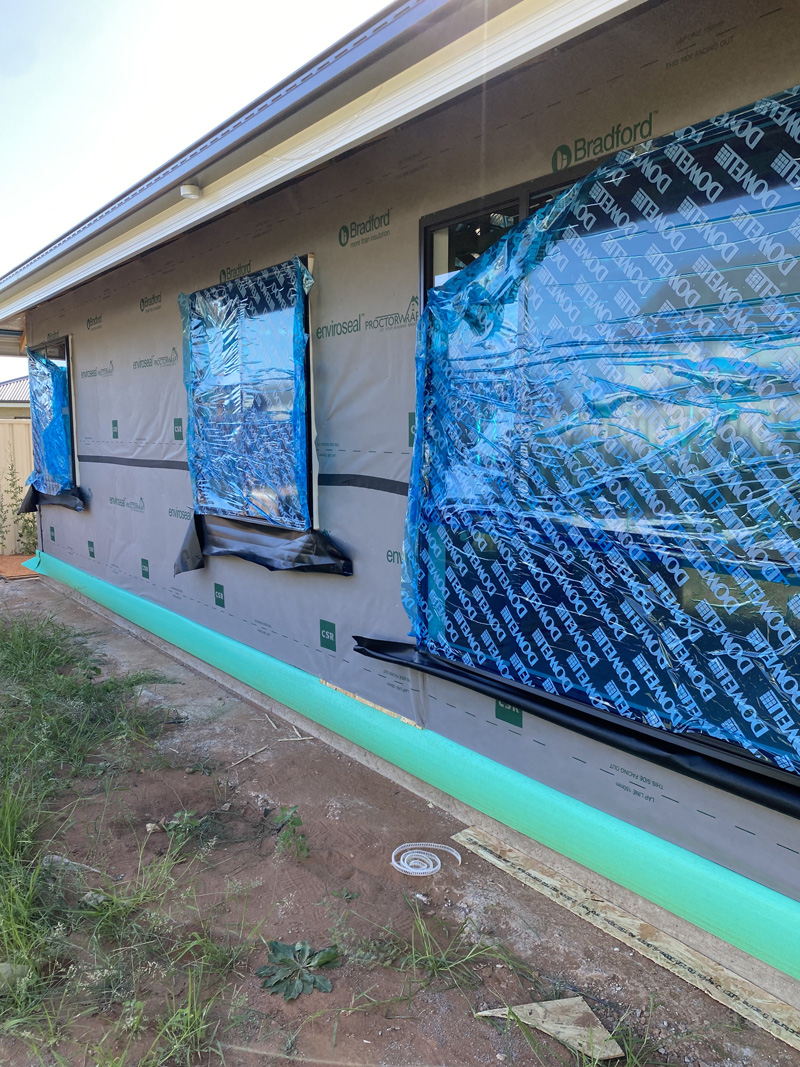 Wall-wrapped house with windows covered in blue protective film