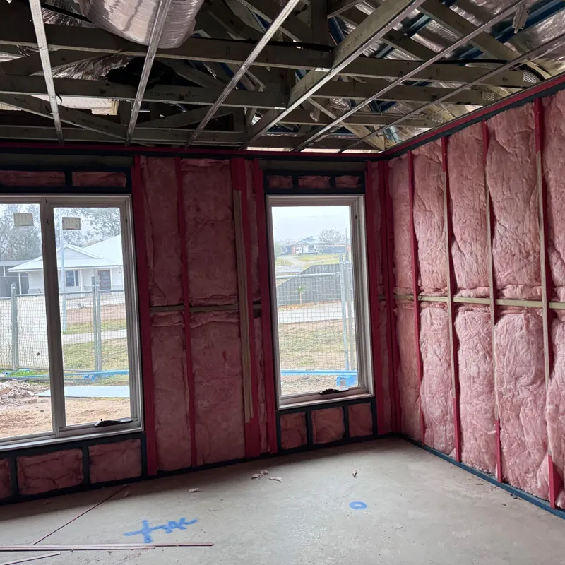 Pink insulation batts in the wall frames around two windows of a new home