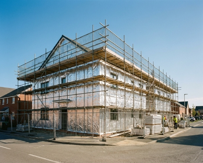 residential building building fully wrapped in reflective insulation wrap Building under construction wrapped in reflective insulation, surrounded by scaffolding