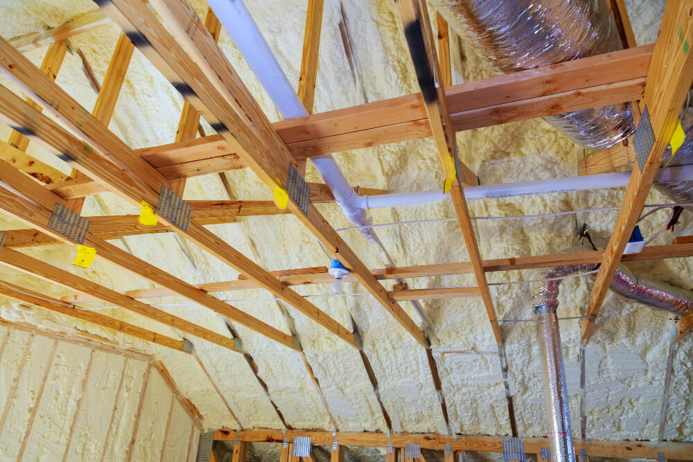 house roof insulation Corowa Spray foam insulation on the underside of a roof between timber trusses and pipes