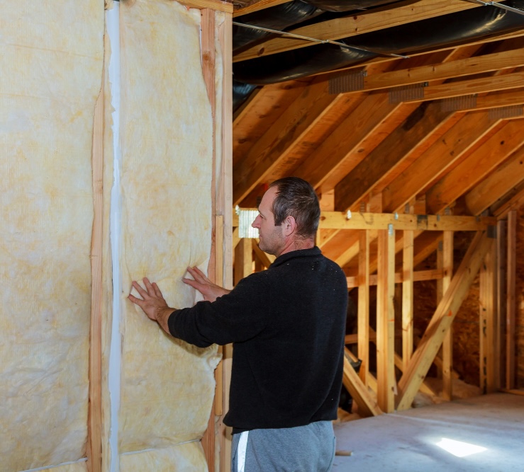 wall insulation service Wangaratta Man pressing an insulation batt into a timber-framed wall